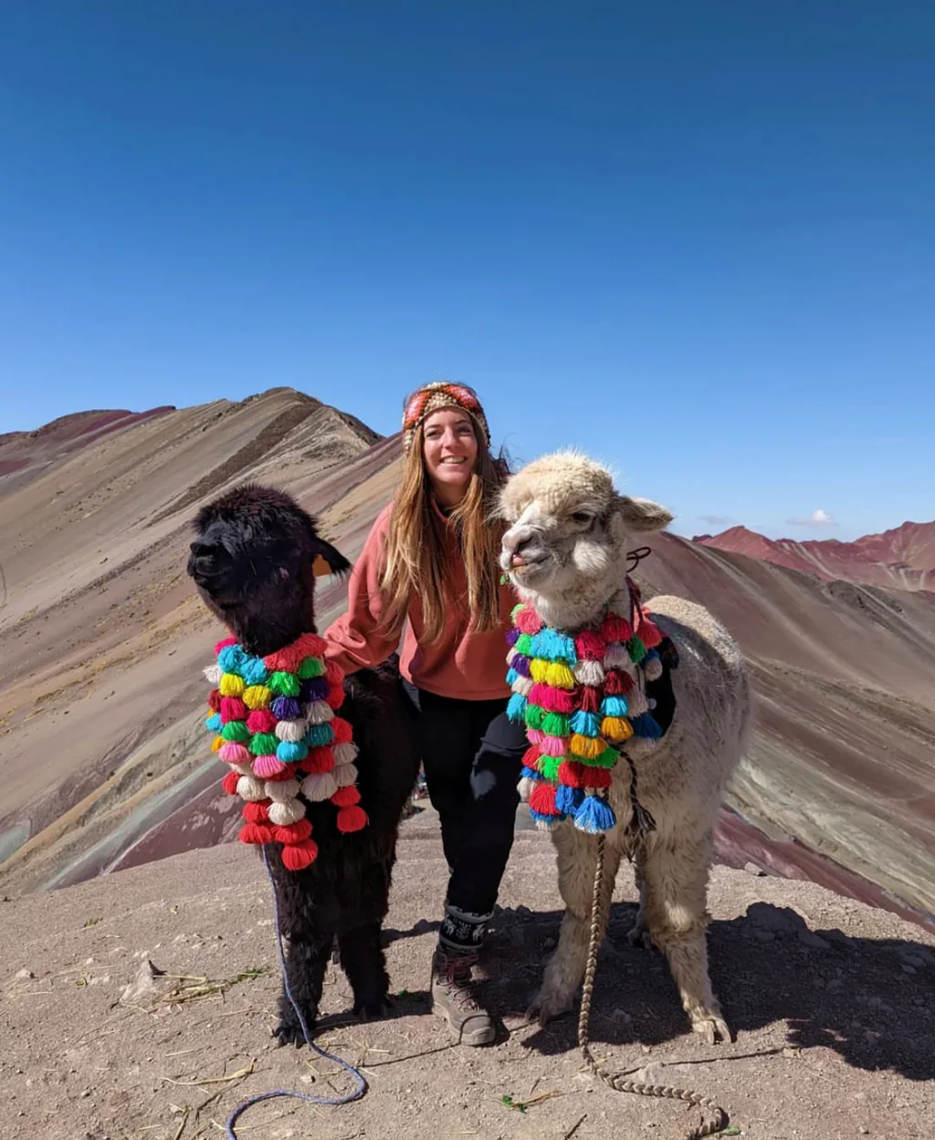 Viajera posando con llamas en la cima de Vinicunca